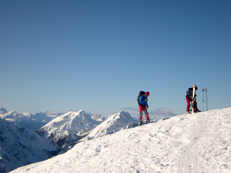 Košuta, smučarja na Velikem vrhu, v panorami Karavank in Julijcev 